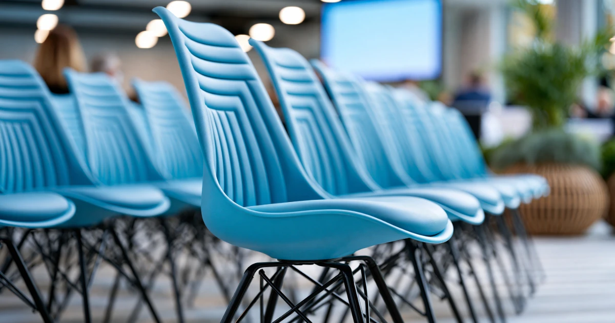 Rows of empty blue conference chairs symbolising the hidden barriers created when event accessibility is not communicated. The image illustrates why promoting BSL interpreters and communication support before an event is just as important as providing them.