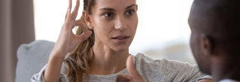 Woman signing in British Sign Language while communicating with another person.